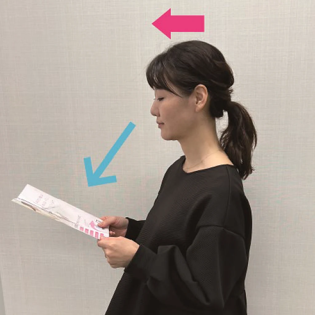 よい例：顔は正面のまま、視線だけを下げて手元の書類を上からのぞき込むように見ている女性